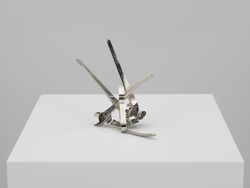 A multi-tool with various implements such as knives and a saw extended, displayed on a white pedestal against a light grey background.