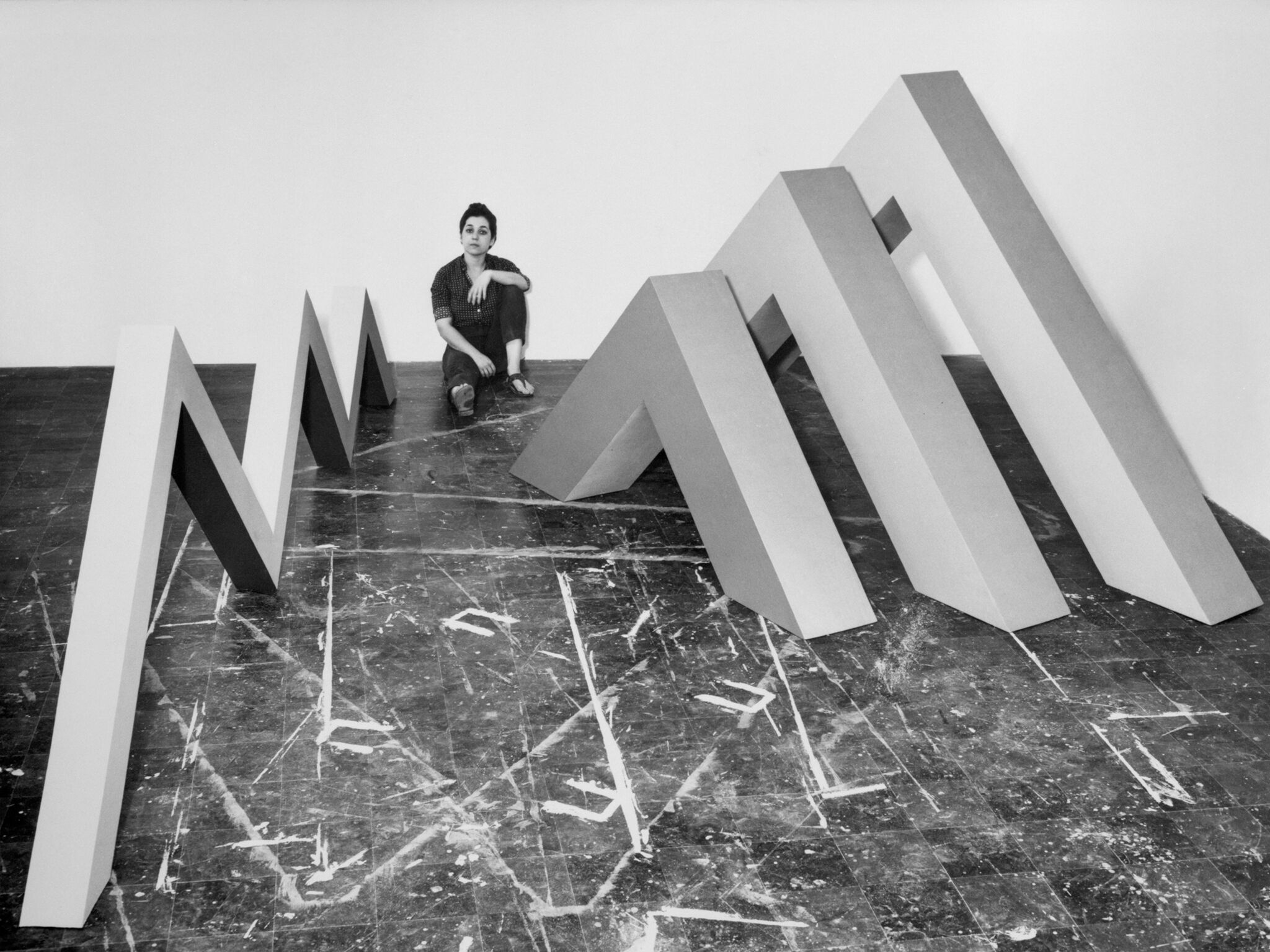 Artist sitting amongst large sculptures