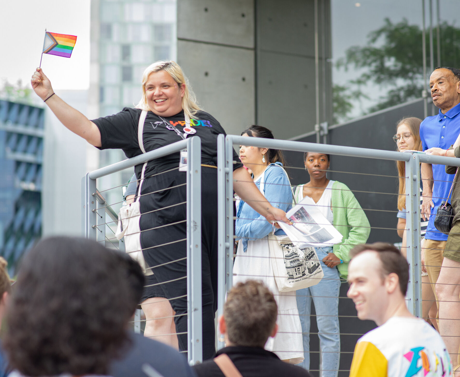 A group of people crowd around a person holding a rainbow pride flag. 