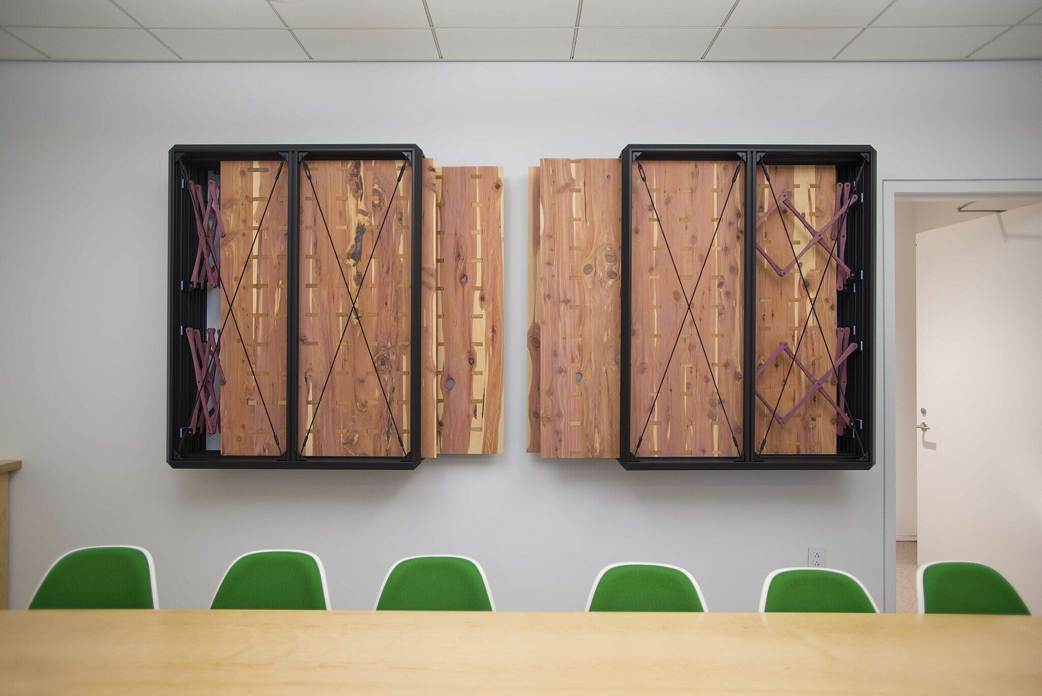 Two rectangular metal boxes containing wooden sheets, mounted on the wall of a conference room