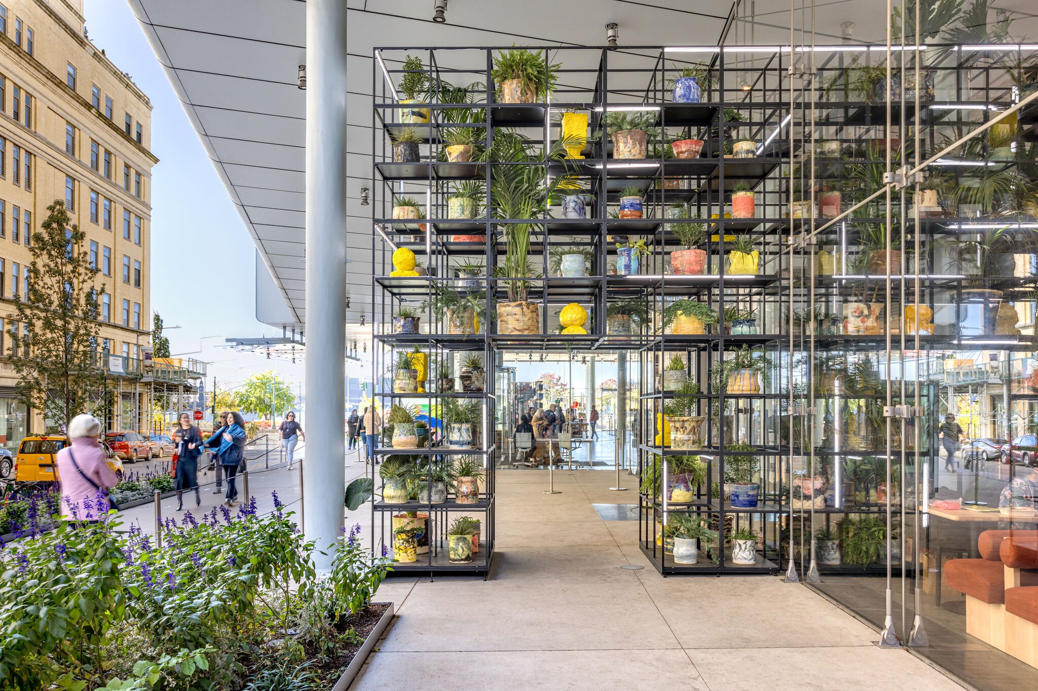 A metal shelf laden with plants, pots, and other items. 