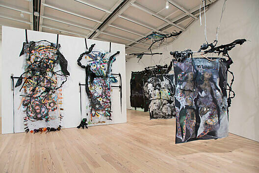 abstract painted sculptural pieces hanging from black straps 