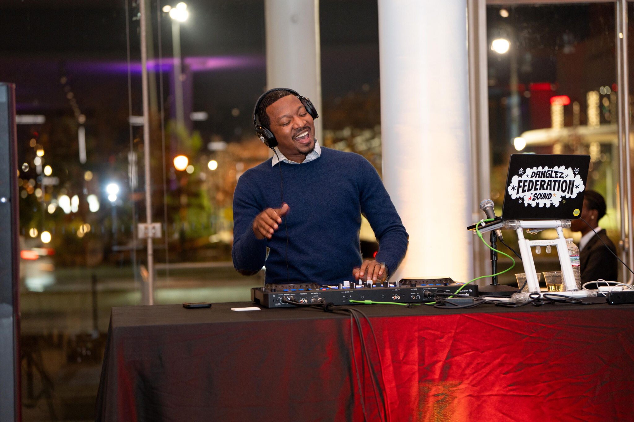 DJ Danglez (Greg Lee) is at his DJ booth, smiling and grooving while playing his set. On his laptop, a sticker reads in all-caps: "Danglez, Federation Sound."