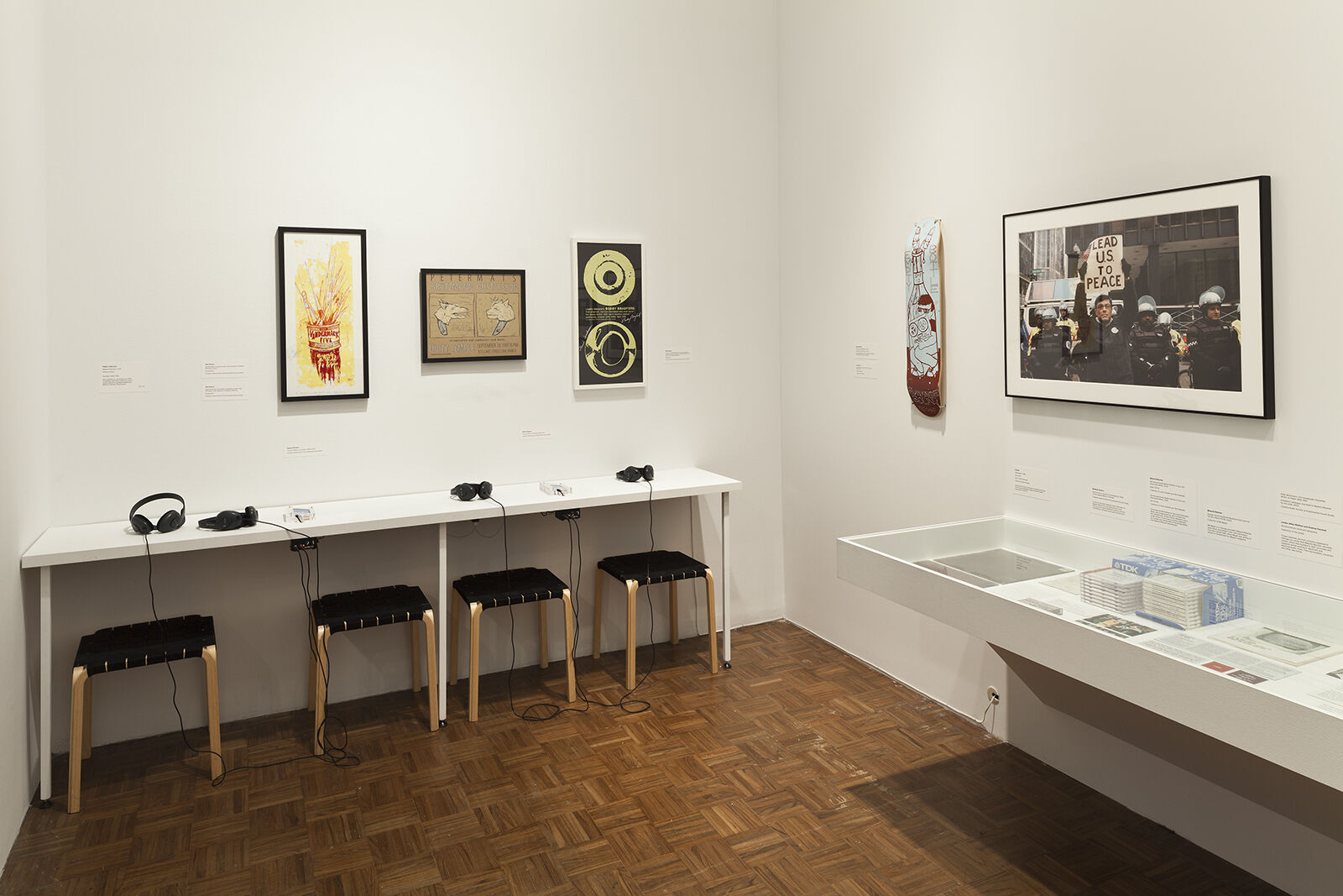 A gallery filled with works of art and a table with several pairs of headphones.