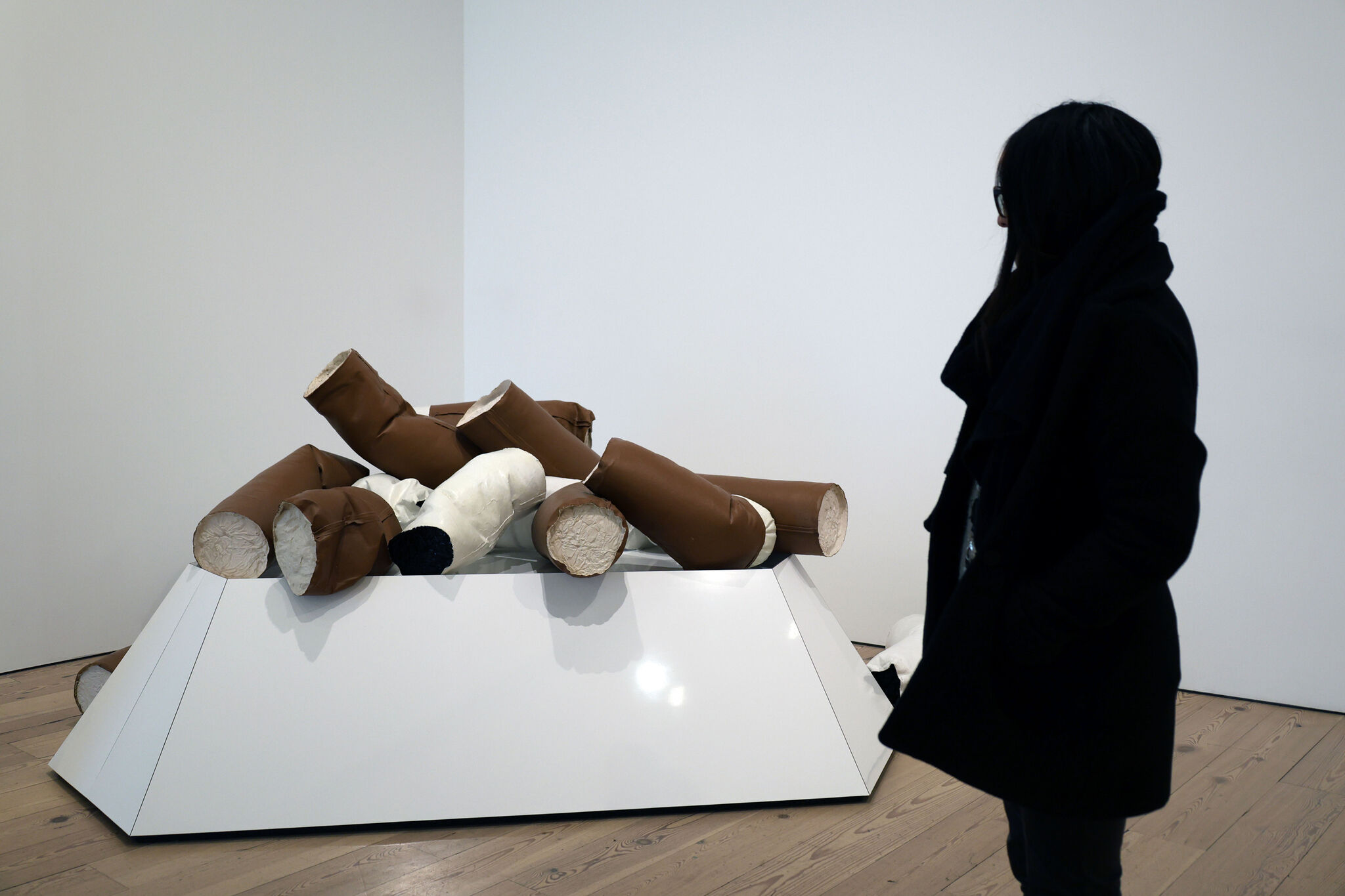 A woman standing near a large sculpture of a pile of cigarettes. 