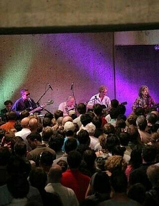 Band performs on stage for an audience viewed from above.