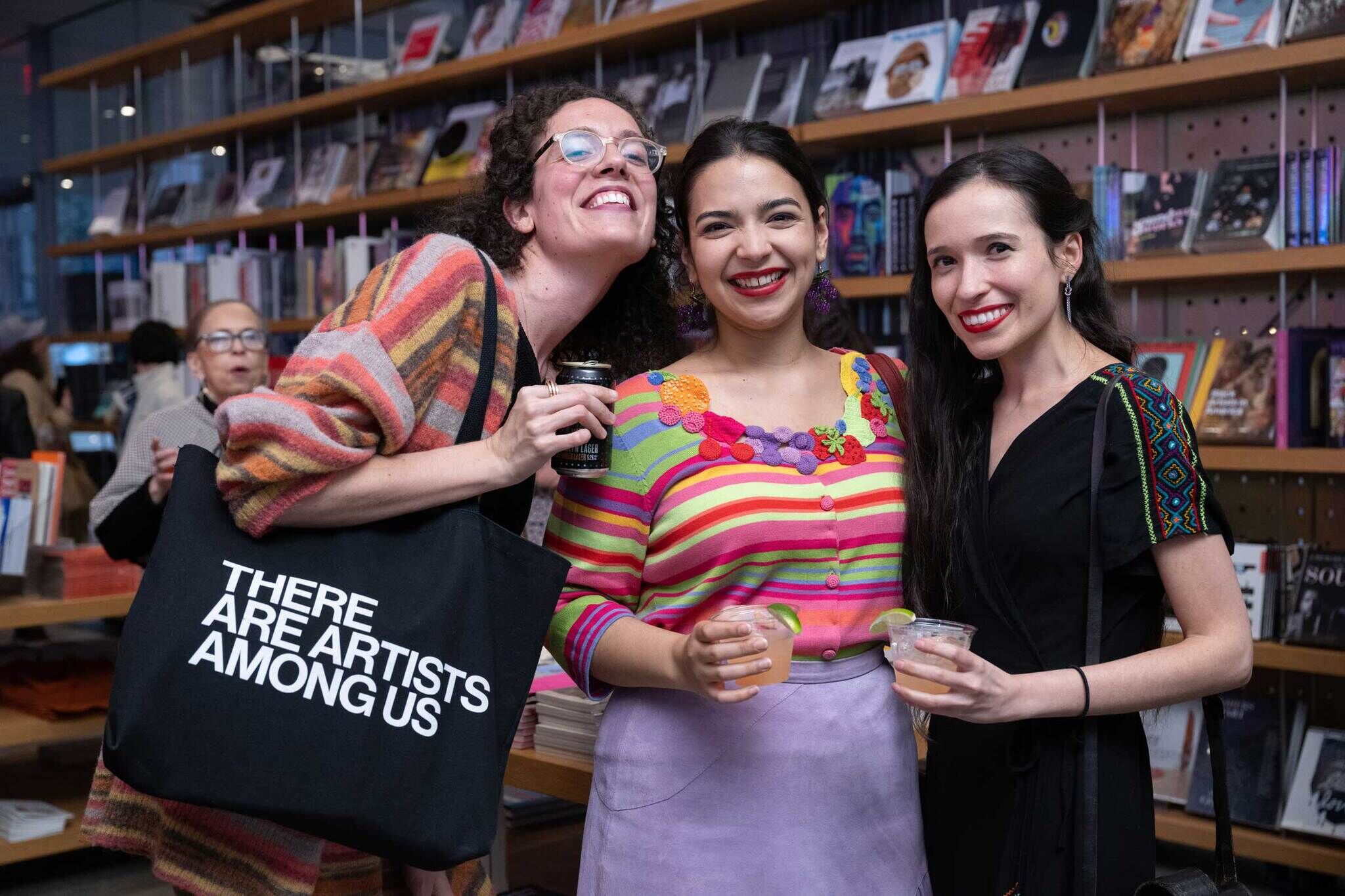 Three people posing for the camera in front of a bookshelf.