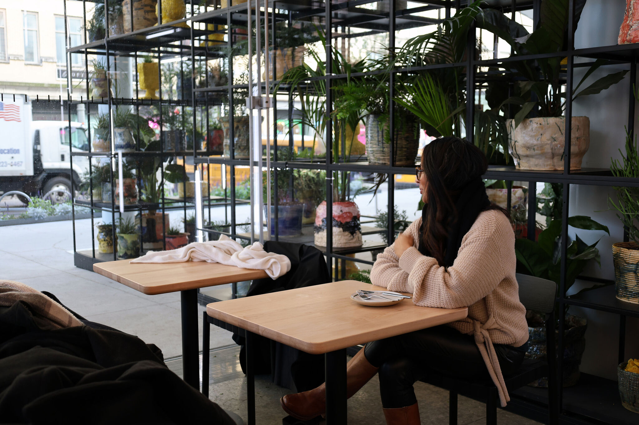 A woman sitting at a table at a cafe with an artwork in the background. 