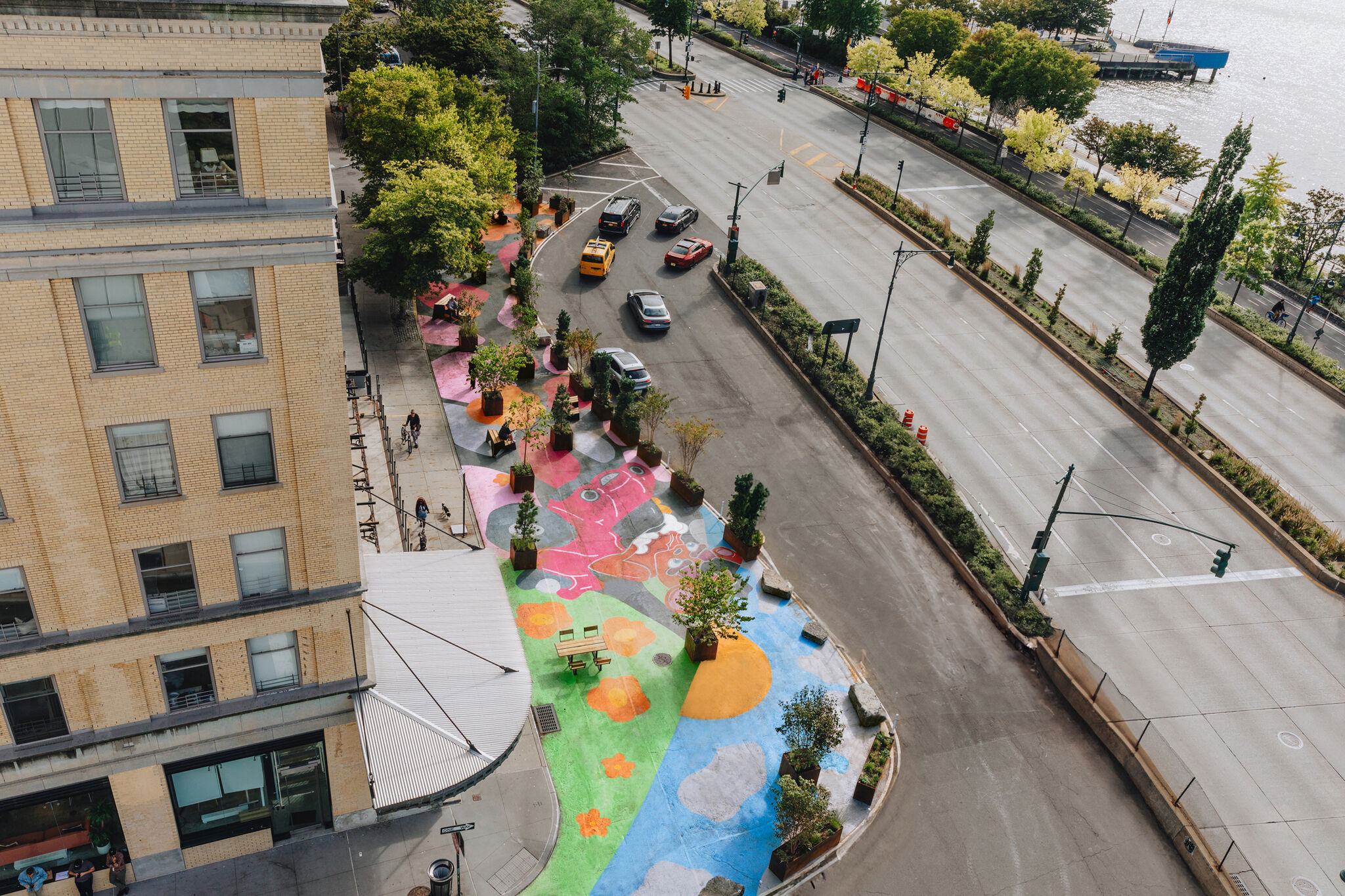 A brightly painted portion of a sidewalk near a tall brick building and the waterfront. 