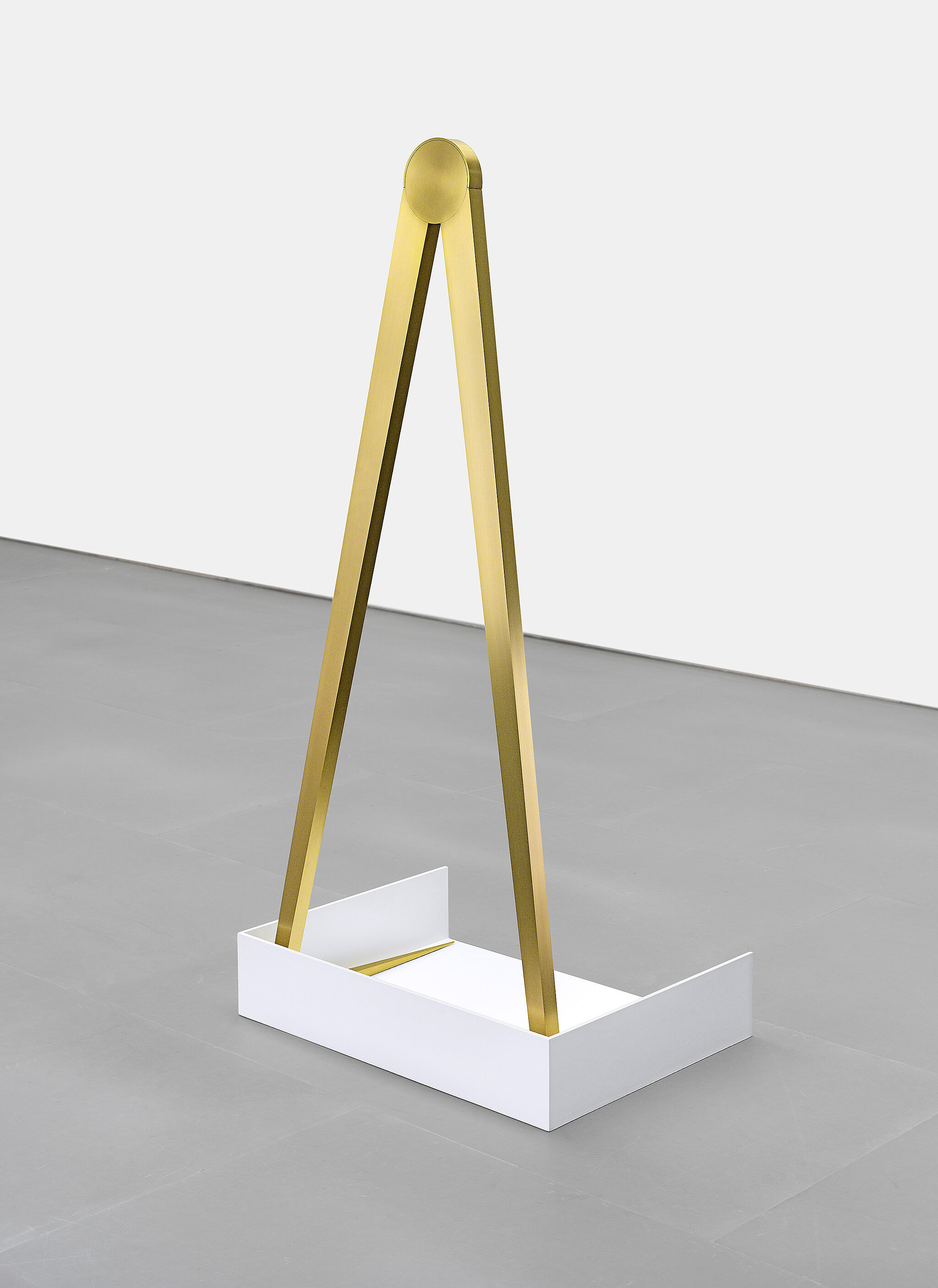 A bronze triangular sculpture on a white rectangular base.