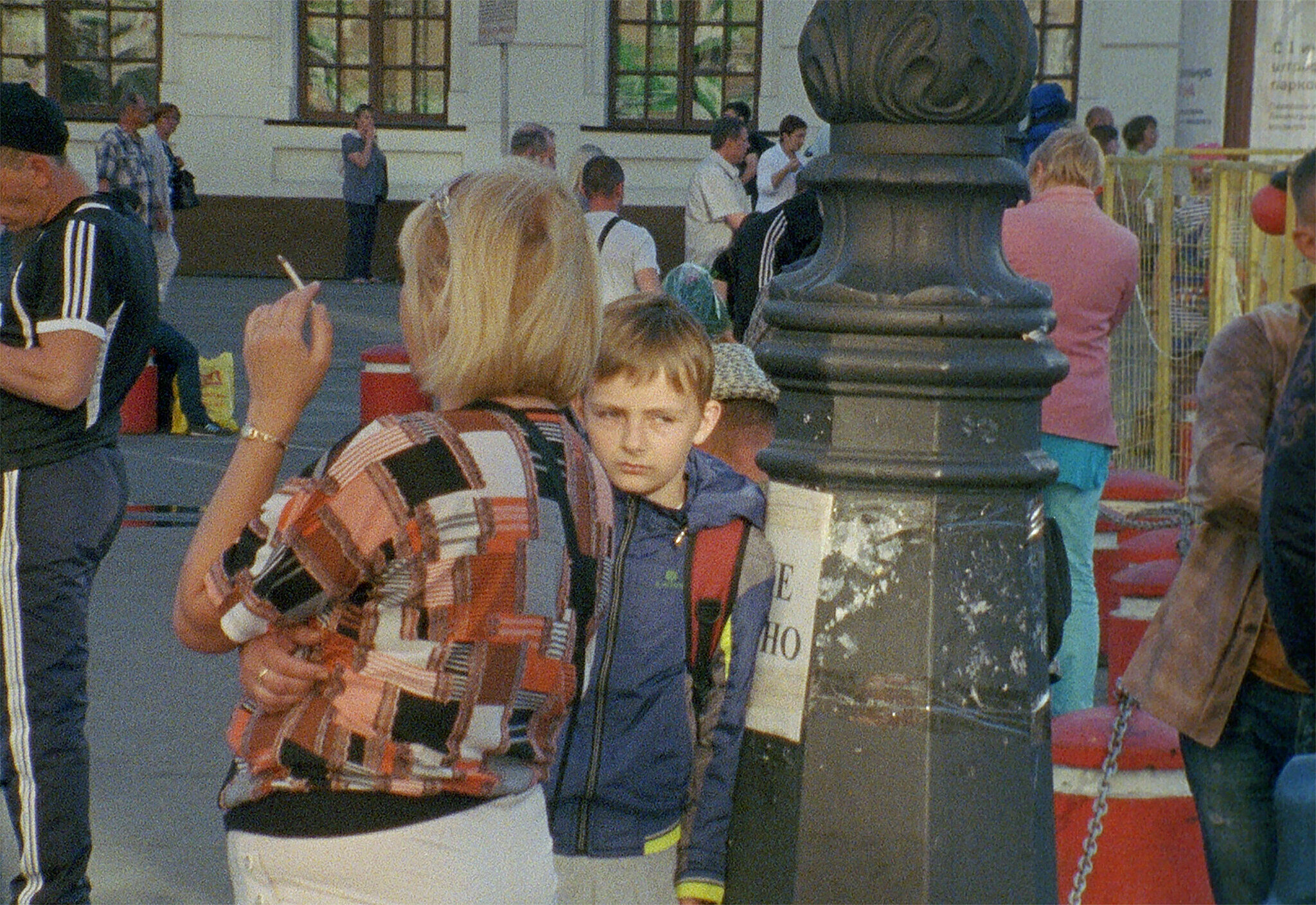 Street crowded with people, woman in foreground smoking cigarette