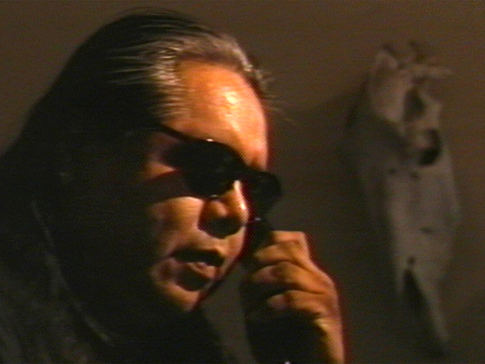 A close-up video still of a man wearing sunglasses.