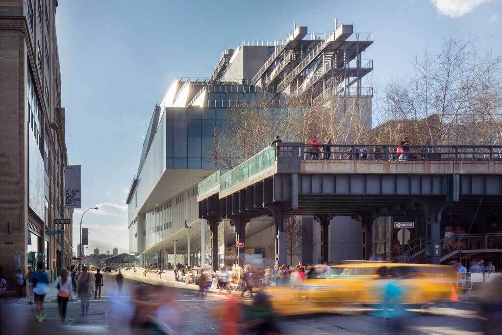 A view of the Museum with people and traffic in the foreground.