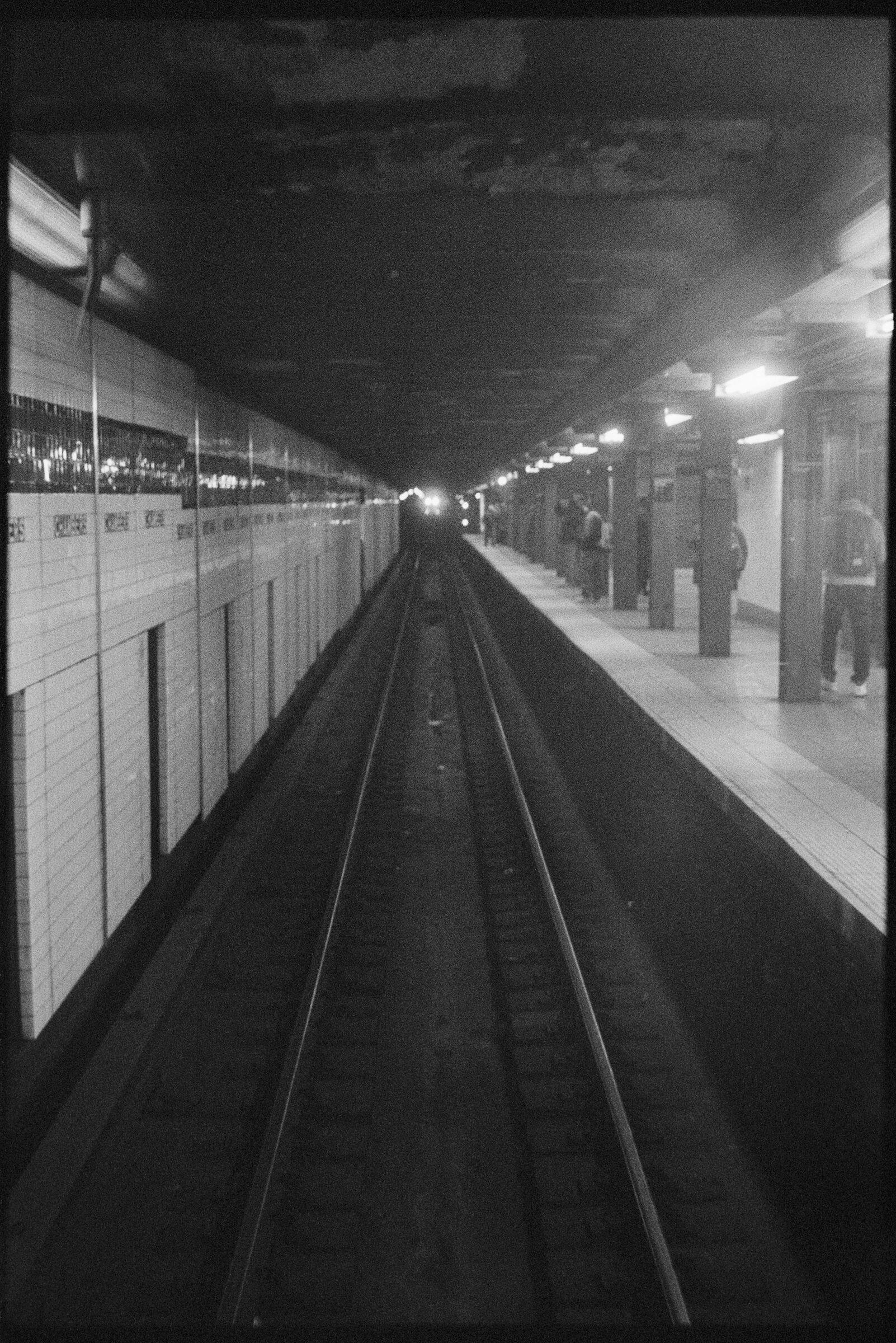 A black and white photograph of an empty subway tunnel. 